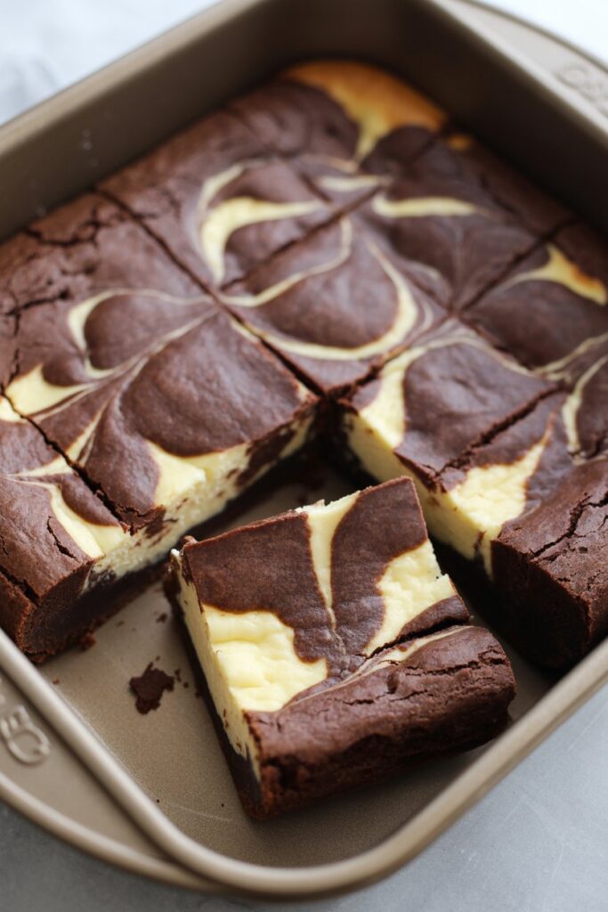 Pan of marbled cheesecake brownies with chocolate and cream cheese swirls.