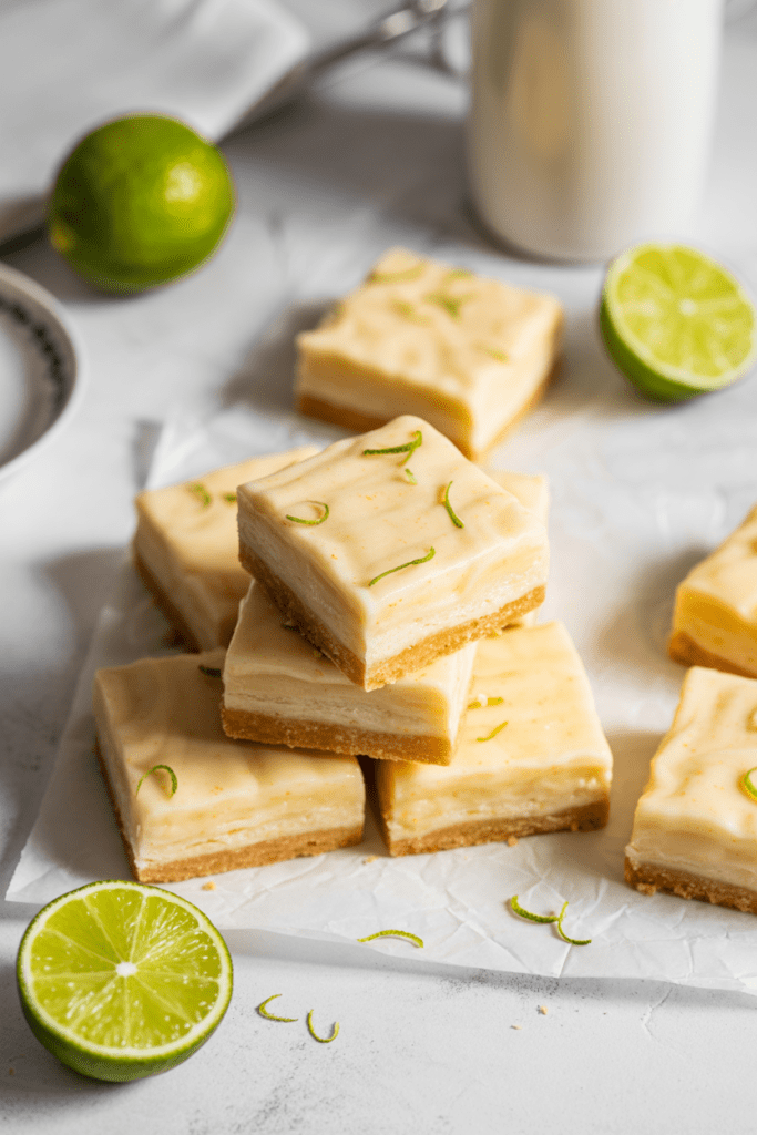 Real-life image of lime shortbread bars, bright citrus desserts with a thick lime filling and buttery crust, arranged neatly on a white surface in a bright modern kitchen with soft shadows and minimal styling.