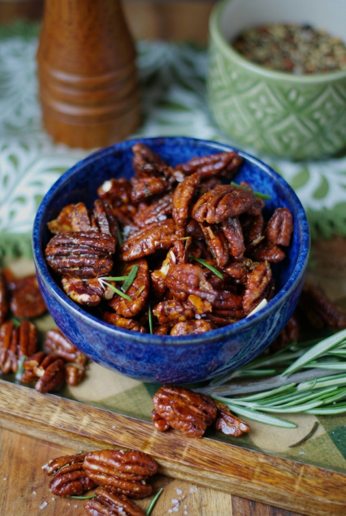 Bowl of toasted rosemary pecans with butter and herb coating, ready for gift jars