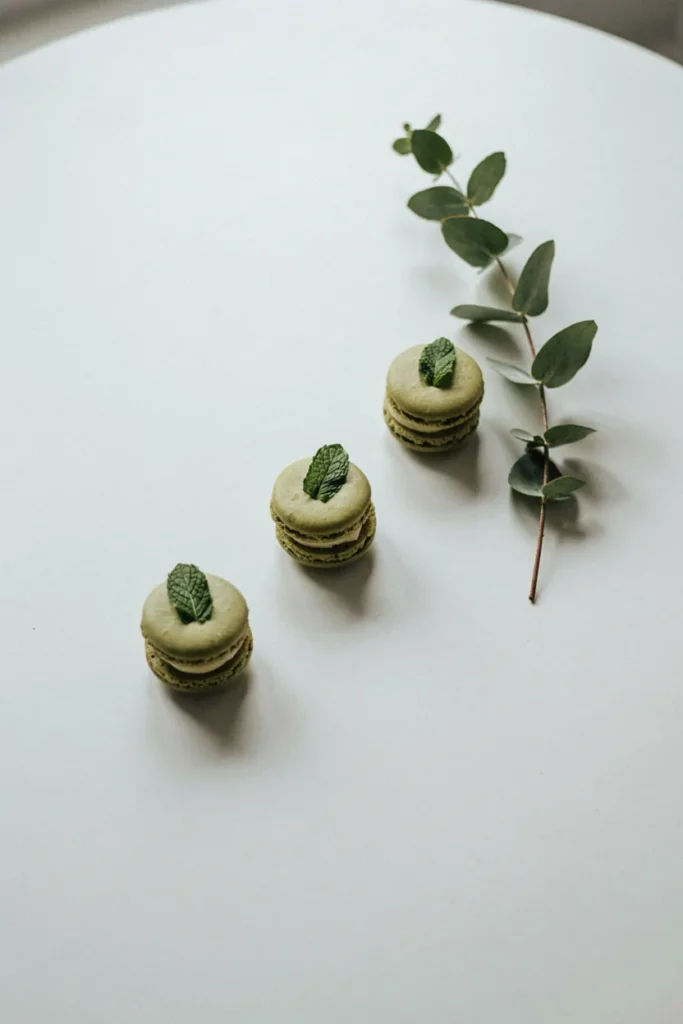 Clean, minimalist white table with just two or three emerald dessert clusters, negative space, single stem greenery