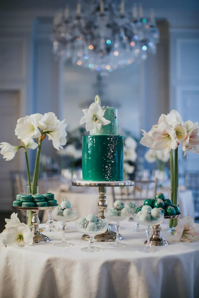 Icy, glamorous dessert table with emerald desserts, silver stands, white amaryllis, glossy finishes