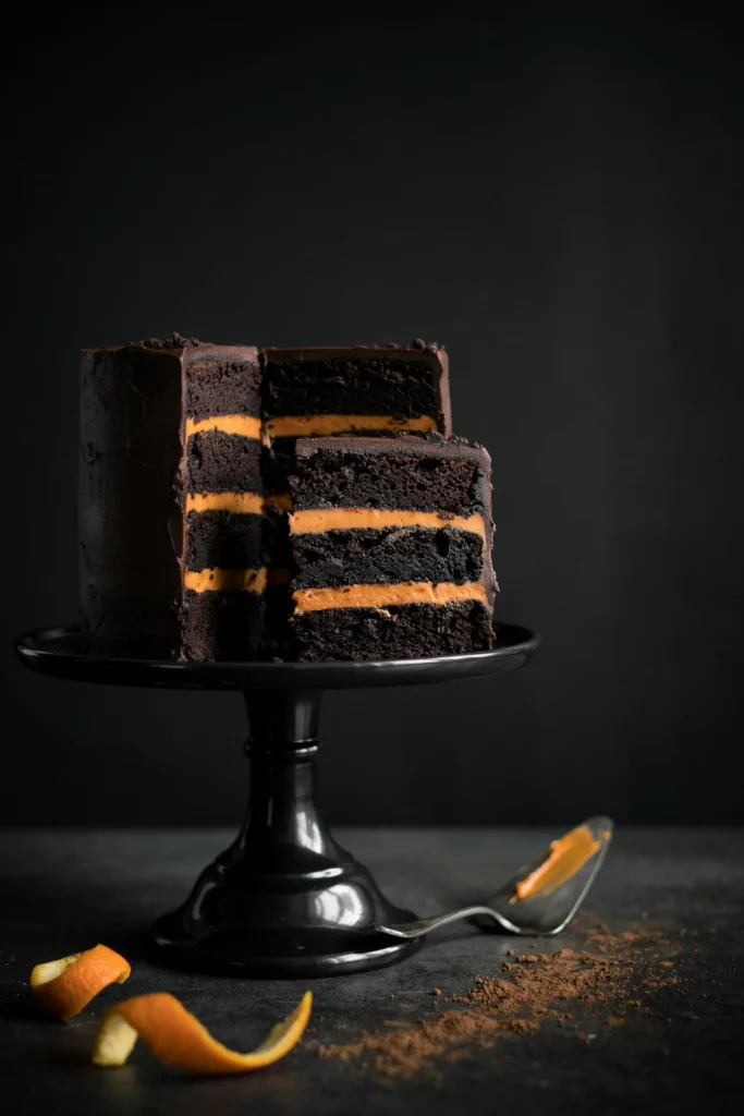 Black cocoa velvet cake sliced open showing bright orange buttercream filling