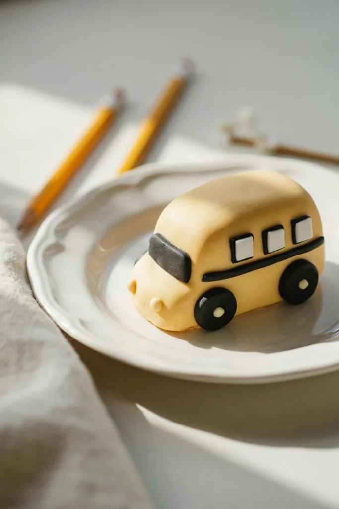 Banana cupcake decorated with yellow fondant shaped like a school bus with black wheels and small windows