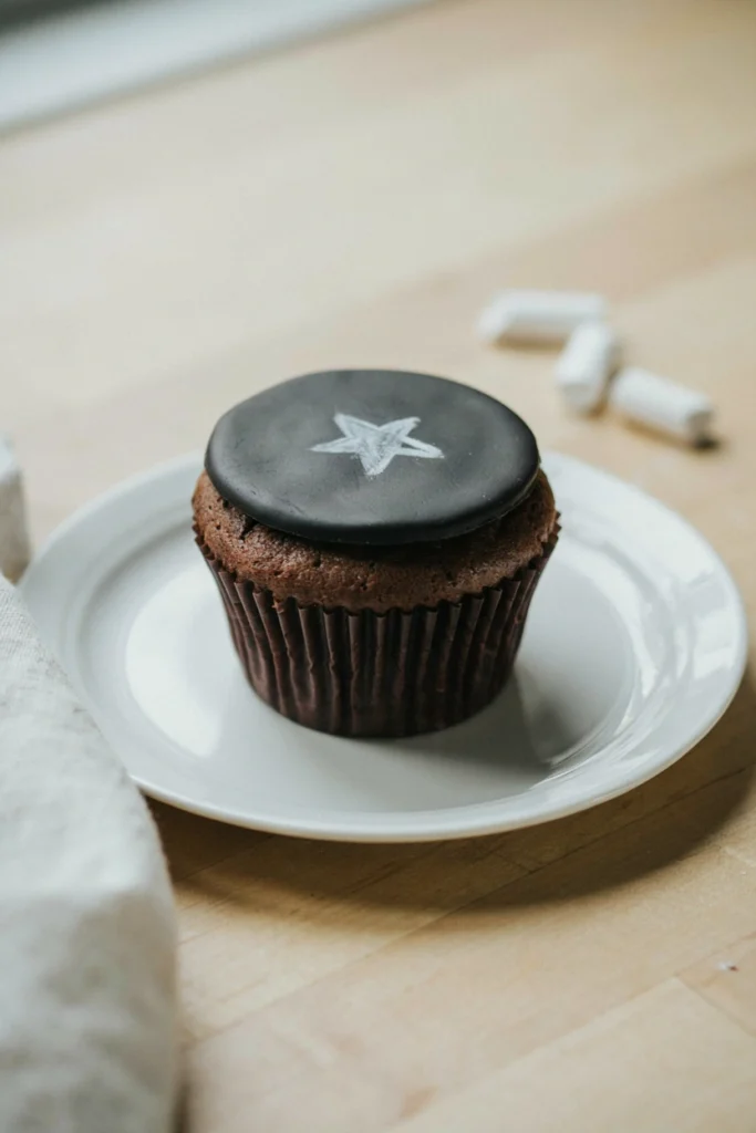 Chocolate cupcake topped with a flat black fondant chalkboard circle hand-lettered A+ in white edible marker