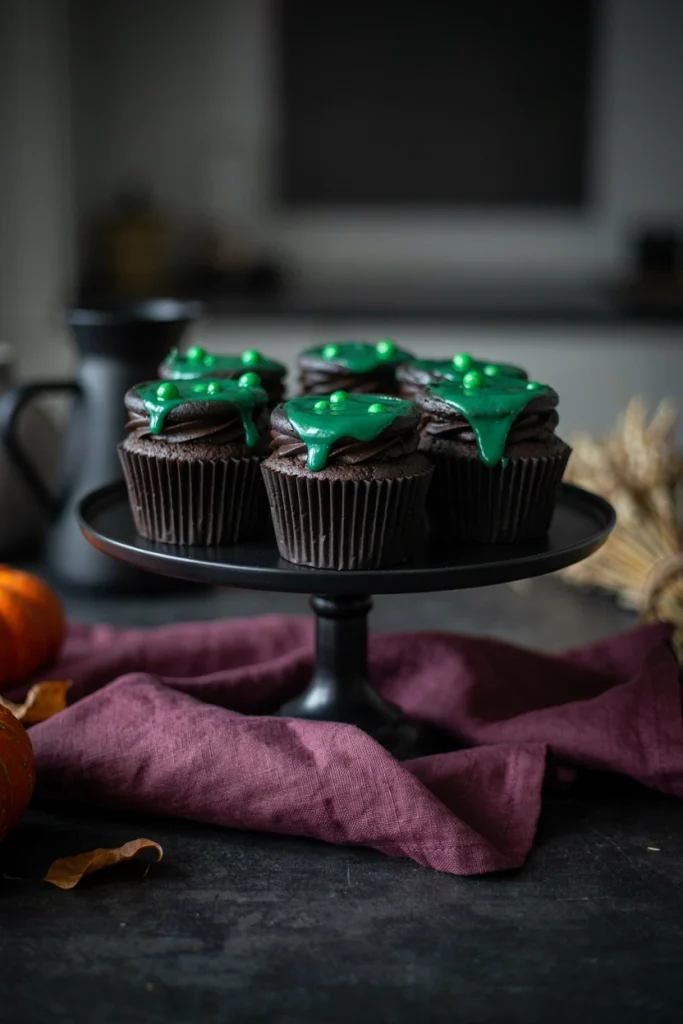 Black frosted cupcakes with a green candy 'bubbling potion' drip and a plastic cauldron pick
