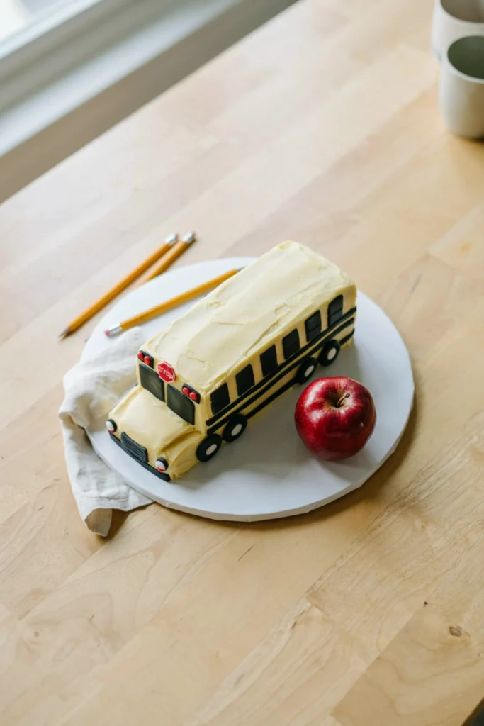 Yellow school bus sheet cake decorated with black fondant wheels and windows