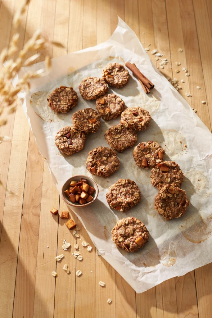 No-bake apple cinnamon oat cookies studded with dried apple pieces on parchment paper