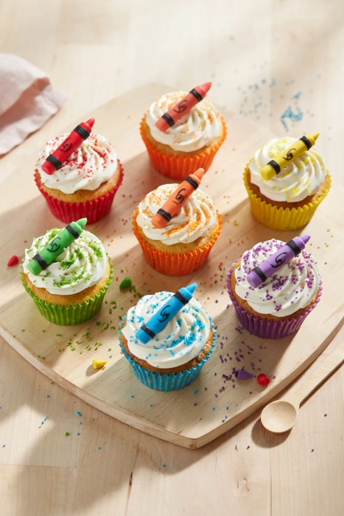 Vanilla cupcake piped with six rainbow-colored frosting stripes resembling a box of crayons