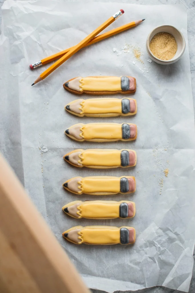 Pencil-shaped sugar cookies decorated with yellow, pink, and gray icing for back to school