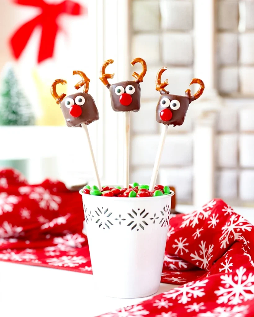 Chocolate-dipped marshmallow pops decorated as reindeer standing in a decorated jar