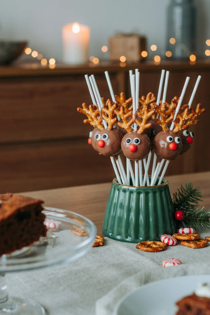 Chocolate-coated cake pops decorated as reindeer with pretzel antlers standing in a stand