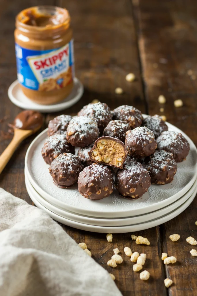 Round peanut butter snowballs rolled in powdered sugar, piled in a white bowl
